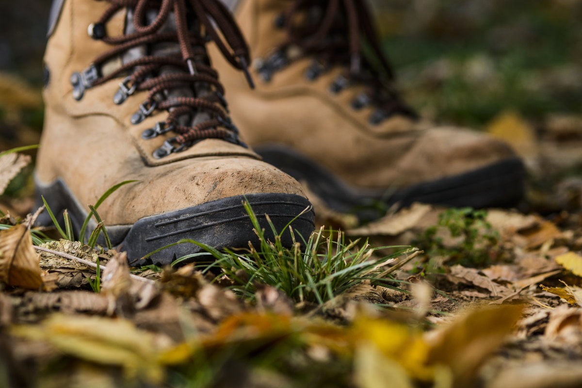 Close up of a pair of light brown leather walking boots bearing worn by a walker.