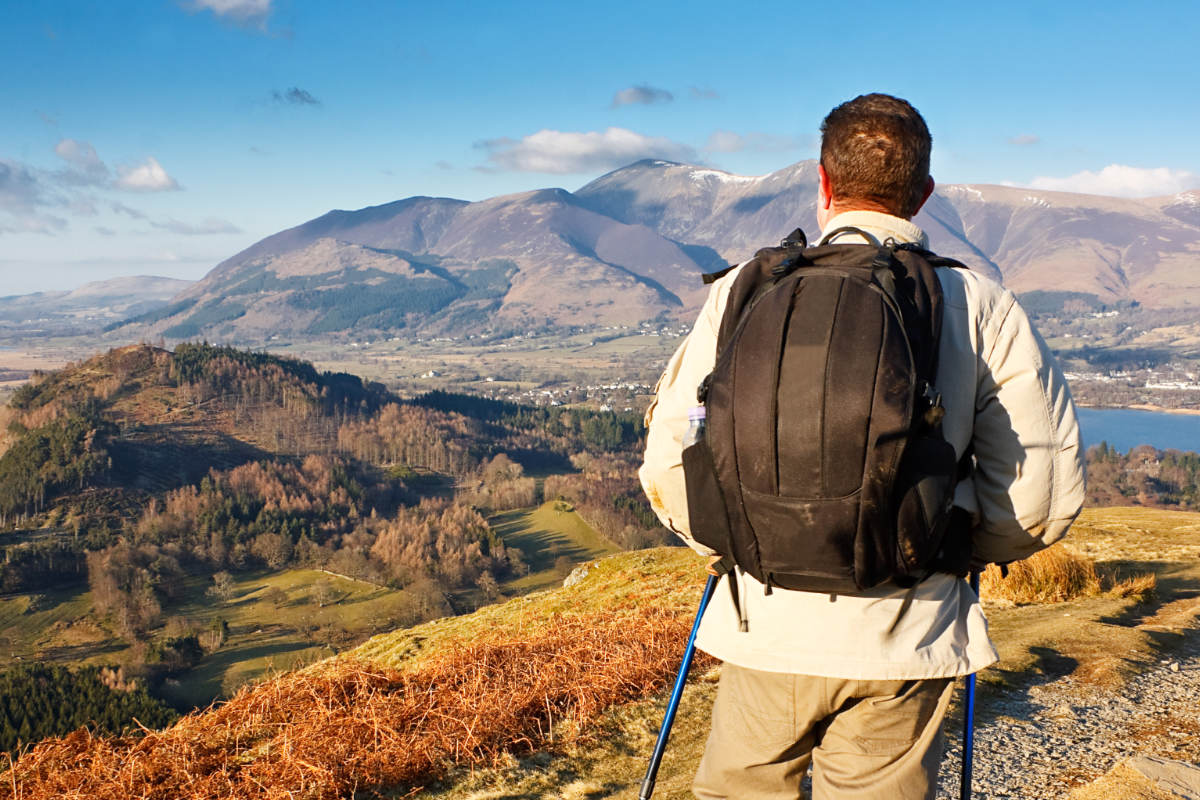 Male walker wearing a backpack, admiring the views in the UNESCO Lake District