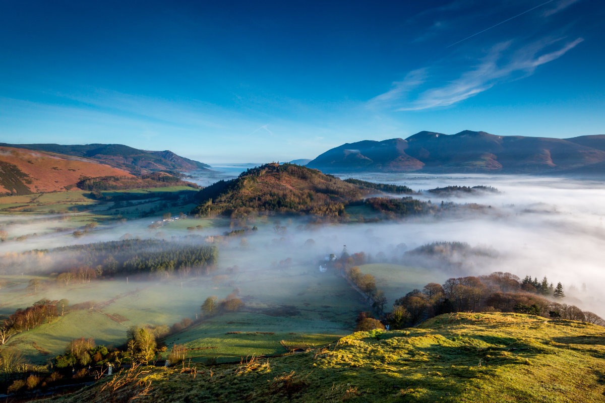 View from Catballs in the Lake District across mist covered forests, open moors and Derwentwater.