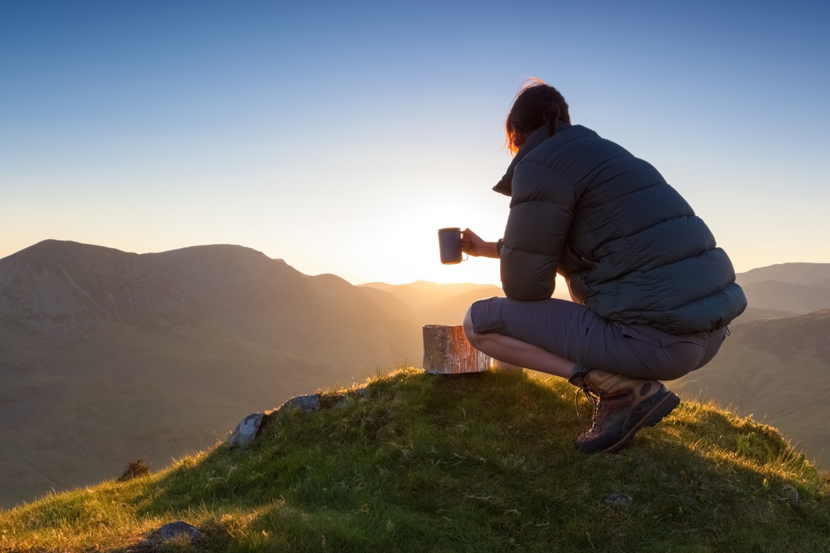 Male hiker enjoying a hot drink from his backpacking stove in the Lake District